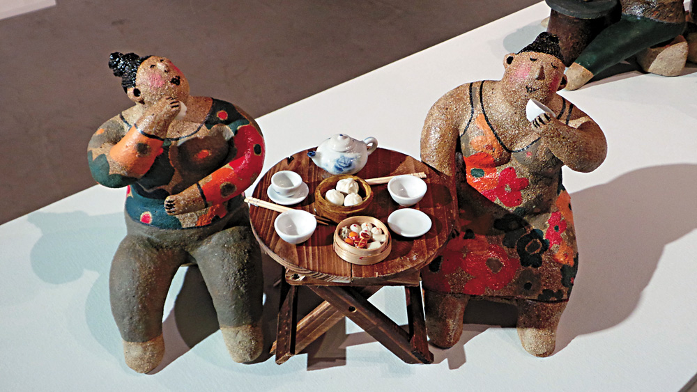 图:作品《撑抬脚》展现香港饮茶文化 纵观西方当代雕塑的发展,从罗丹到马约尔,再到布朗库西与贾科梅蒂,你会发现具象雕塑正一步步走向抽象,走向形式,走向媒介,让人误以为只有难以解读的作品才是雕塑的正道。本土雕塑家、陶艺家李慧娴却对此般正道做出不同诠释,她以一对对憨态可掬的肥佬肥婆让观众会心一笑,而融入了香港饮茶文化、无厘头式幽默的陶塑人物均彰显出李慧娴轻松闲适、悠然自得的创作式生活。大公报记者周婉京 文、图 我的创作灵感来自哪里?答案很简单生活。我的作品无一不由生活出发