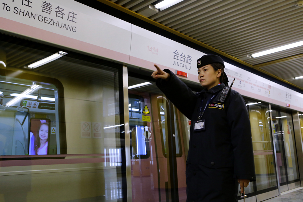 图:北京地铁14号线金台路站内,工作人员确认地铁车门关闭中新社