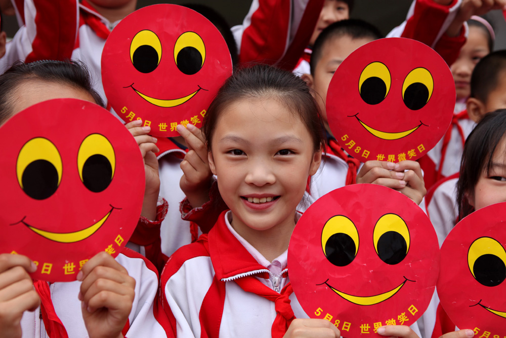 5月7日,河北省峰峰矿区春光小学学生们手举笑脸卡迎接"世界微笑日".