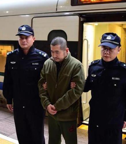 图:18日,在汉口火车站,犯罪嫌疑人王某在警方押送下抵达武汉/新华网